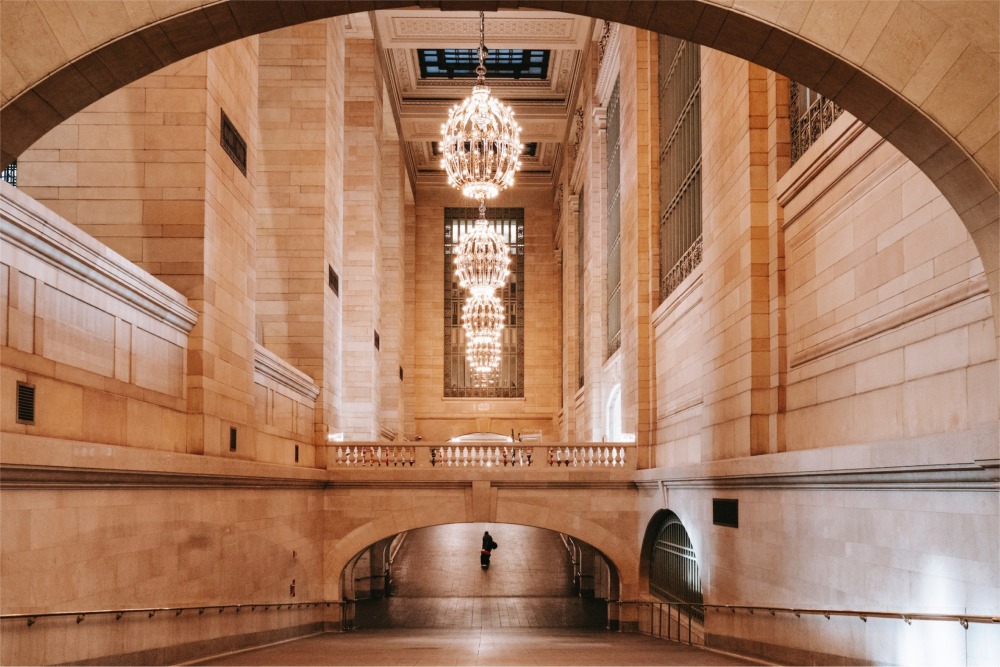 This photograph shows a ramp to the lower concourse in Grand Central Terminal and four large round Beaux-Arts chandeliers. New York City ny nyc