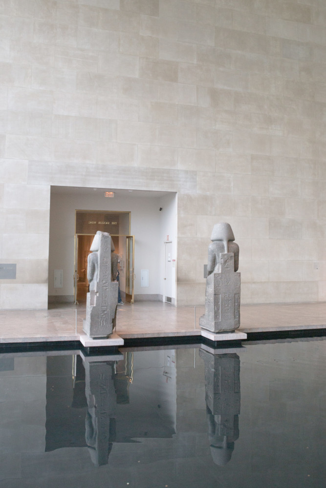 This photograph shows two statues (rear view) of Amenhotep III at the Temple of Dendur in the Metropolitan Museum of Art in New York.