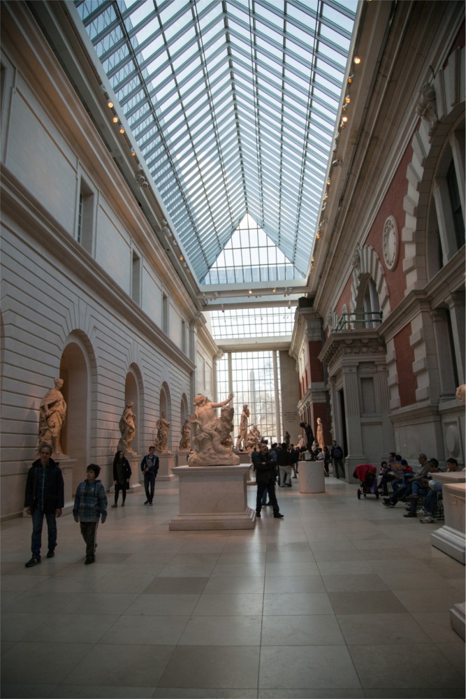 This photograph shows people in the Carroll and Milton Petrie European Sculpture Court at the Metropolitan Museum of Art in New York City.
