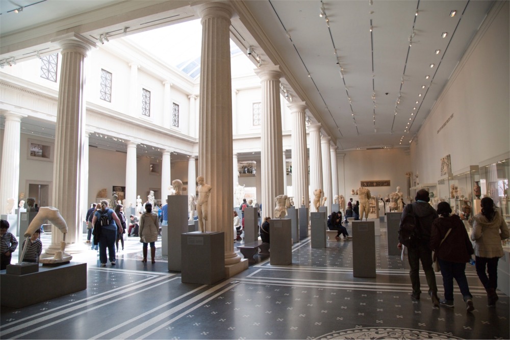 This photograph shows a gallery of stone sculptures and other artifacts from ancient Rome and Greece. The gallery is at the Metropolitan Museum of Art in New York City.