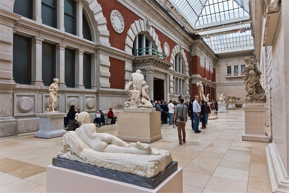 This photograph shows people in the Carroll and Milton Petrie European Sculpture Court at the Metropolitan Museum of Art in New York City.