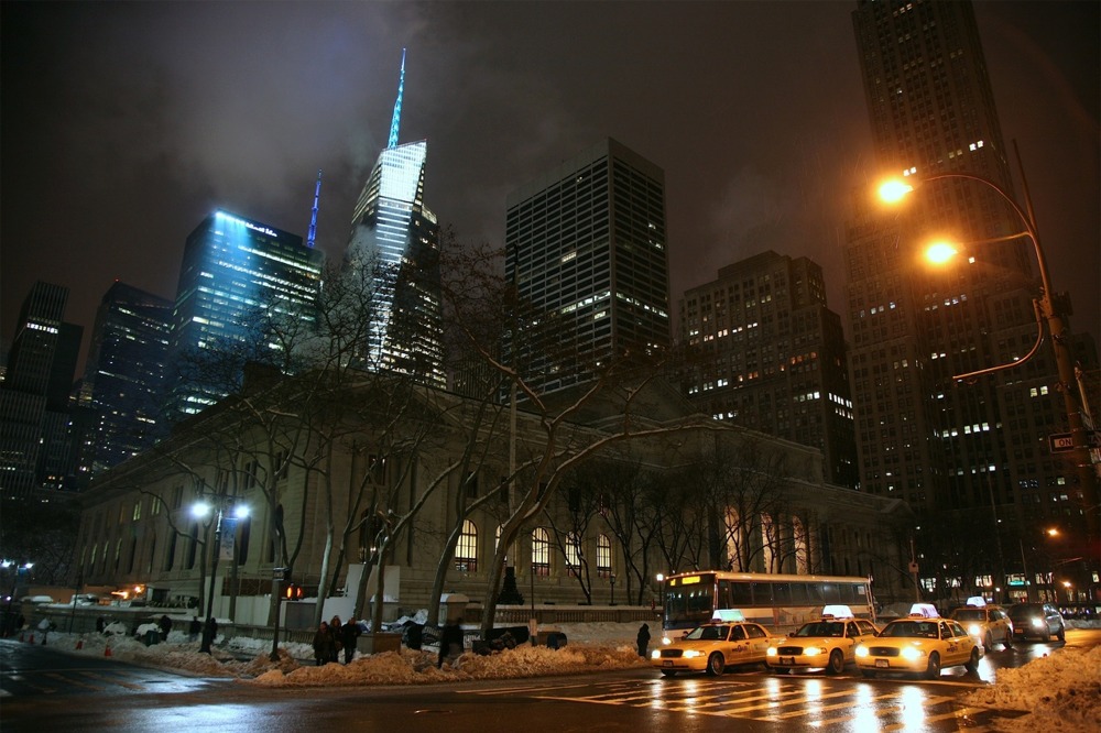 The New York Public Library main branch facade along Fifth Avenue at its intersection with East 41st Street during night time in winter.